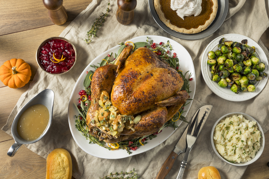 A complete turkey dinner with cooked whole turkey in the center and vegetable sides around it